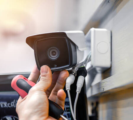 Close-up of surveillance camera installation, male hand holds cctv camera Close-up of surveillance camera installation, male hand holds cctv camera